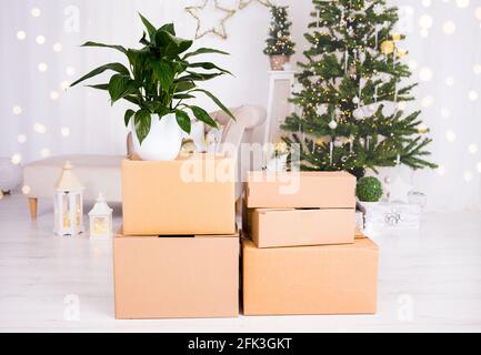 In Movimento per la casa nuova per il concetto di Natale. Focus sulla delocalizzazione di cartone scatole e albero di Natale decorato con presenta sotto di esso sullo sfondo Foto Stock