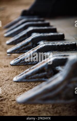 I denti della benna dell'escavatore si avvicinano. Bassa profondità di campo. Messa a fuoco selettiva. Foto Stock