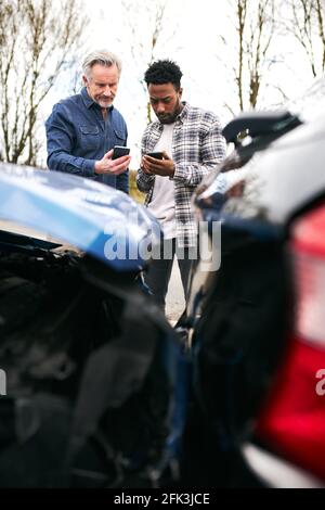 Due conducenti maschi sul lato della strada che si scambiano auto dettagli dell'assicurazione dopo l'incidente stradale Foto Stock