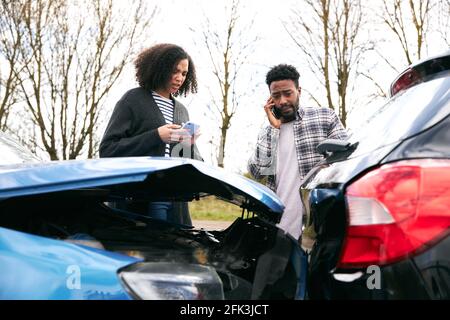 Coppia a lato della strada scambiando i dettagli dell'assicurazione auto dopo un incidente stradale Foto Stock