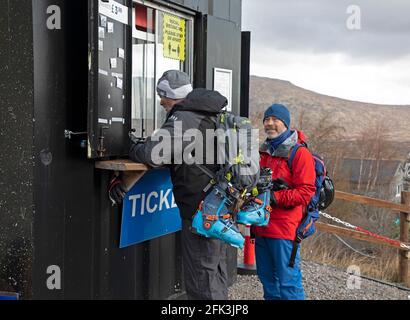 Glencoe, Lochaber, Scozia, Regno Unito. 28 aprile 2021. Questi uomini viaggiarono da Aberdeen per visitare la tranquilla pista sciistica di Glencoe Mountain Resort ed eccitati dopo che le restrizioni di Lockdown si sono allentate per comprare i loro biglietti e salire sulla seggiovia per ottenere un po' di sci in prima che la neve sia lasciata sparisca dalle piste di montagna. Foto Stock