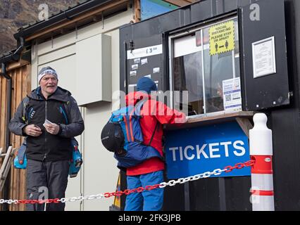 Glencoe, Lochaber, Scozia, Regno Unito. 28 aprile 2021. Questi uomini viaggiarono da Aberdeen per visitare la tranquilla pista sciistica di Glencoe Mountain Resort ed eccitati dopo che le restrizioni di Lockdown si sono allentate per comprare i loro biglietti e salire sulla seggiovia per ottenere un po' di sci in prima che la neve sia lasciata sparisca dalle piste di montagna. Foto Stock