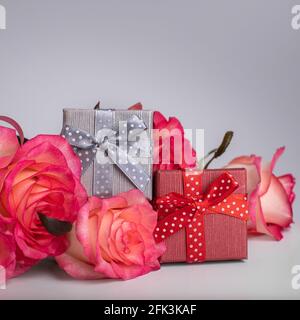 Confezione regalo in argento e rosso per un gioiello e rose rosa. Scatole di gioielli. Sorpresa per la tua ragazza Foto Stock