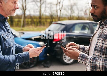 I conducenti più giovani e più anziani al lato del cambio di strada assicurazione auto dettagli dopo l'incidente stradale utilizzando telefoni cellulari Foto Stock