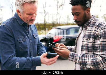 I conducenti più giovani e più anziani al lato del cambio di strada assicurazione auto dettagli dopo l'incidente stradale utilizzando telefoni cellulari Foto Stock