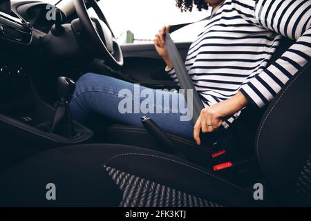 Primo piano del conducente femmina nella cintura di sicurezza di fissaggio della vettura su inizio del viaggio Foto Stock