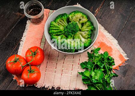 Mazzi di broccoli verdi pronti a cucinare. Broccoli in una piastra bianca su un tavolo di legno Foto Stock