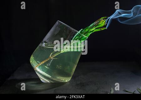 Una bevanda fredda con rosmarino affumicato su sfondo nero, primo piano, isolato Foto Stock