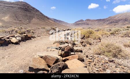 Strada della polvere che conduce in una valle in un paesaggio desertico Foto Stock