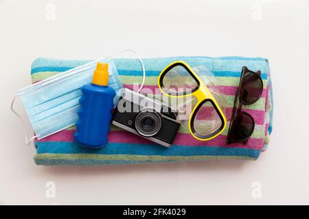 maschera protettiva e crema solare su una spiaggia di vacanza estiva asciugamano Foto Stock