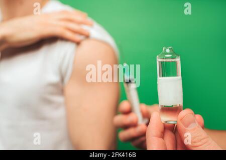 Primo piano tenendo una fiala prima dell'iniezione, isolata su sfondo verde Foto Stock