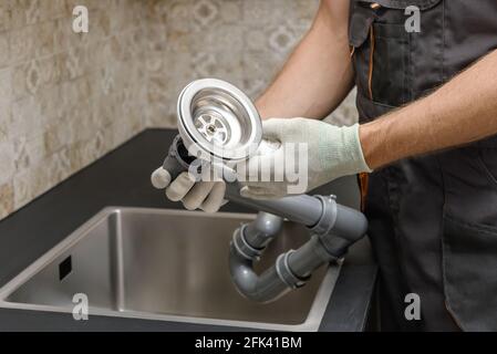 Un lavoratore sta installando uno scarico della fognatura per il lavandino della cucina. Foto Stock