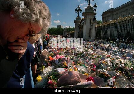 Principessa Diana morte 31 agosto 1997Mornatori che posano e osservano fiori Lasciato fuori Buckingham Palace in memoria della principessa Diana Who È stato ucciso in un incidente d'auto a Parigi Foto Stock