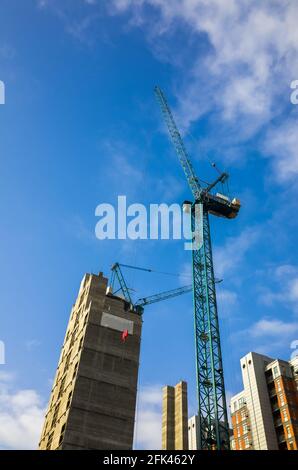 Gru alta che opera su un cantiere di alti appartamenti nella città di Leeds, Inghilterra, Regno Unito. Costruzione, sviluppo, gru e costruzione Foto Stock