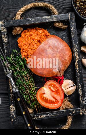 Mallorcan Sobrassada salumi di carne di maiale in un vassoio di legno sfondo di legno nero. Vista dall'alto Foto Stock