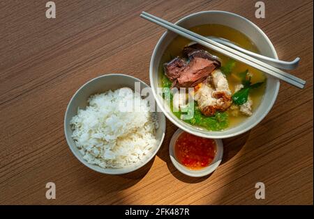 Vista dall'alto pasto asiatico, una ciotola di zuppa di sangue di maiale e maiale con riso bianco a vapore e salsa piccante-acida, luce naturale sul tavolo. Zuppa di sangue di maiale e maiale Foto Stock