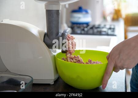 Donna che usa il macinacaffè per la preparazione della carne macinata in cucina Foto Stock