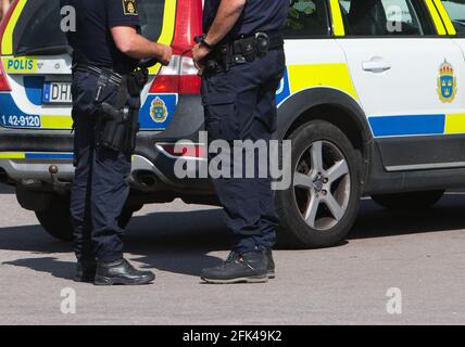 Ufficiali di polizia oltre a una macchina di polizia. Foto Stock