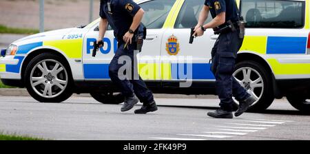 Ufficiali di polizia, con armi disegnate, ad un allarme d'assalto. Foto Stock