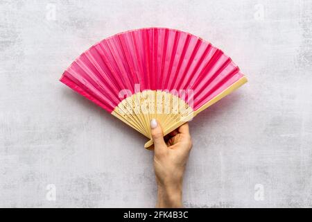 Mano che tiene ventilatore di mano fatto di bambù e carta Foto Stock