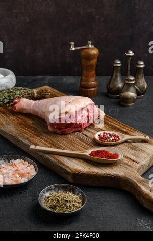 Bastone di tacchino crudo con pelle su tavola di legno Foto Stock