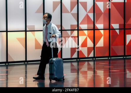 Tokyo, Giappone. 25 Apr 2021. Un viaggiatore che indossa una maschera facciale come precauzione contro la diffusione del coronavirus, cammina attraverso la lobby delle partenze dell'Aeroporto Internazionale Haneda di Tokyo. (Foto di James Matsumoto/SOPA Images/Sipa USA) Credit: Sipa USA/Alamy Live News Foto Stock