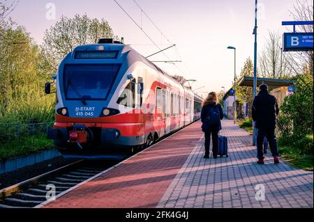 VELENCE, UNGHERIA - 25 APRILE 2021: Panoramica sui passeggeri in attesa del treno delle Ferrovie statali ungheresi che arrivano alla stazione di Agard, Ungheria. Foto Stock