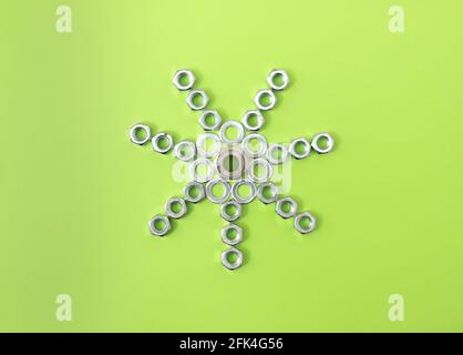 Sole astratto fatto di spaziatori e noci su uno sfondo verde chiaro. Composizione astratta vista dall'alto, posa creativa piatta. Foto Stock