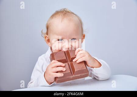 Il bambino mangia un grande pezzo di cioccolato. Il concetto di cibo spazzatura e dieta sana. Cioccolato vegano Foto Stock