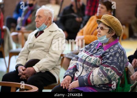 Meeting Club degli anziani. Le persone anziane in maschere mediche si siedono sulle sedie. Foto Stock