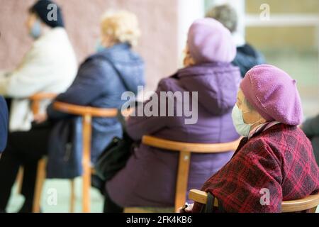 Bielorussia, la città di Gomil, 17 aprile 2021 Meeting Club degli anziani. Un uomo anziano in una maschera medica, sparato in profilo. I posti a sedere degli anziani a un Foto Stock