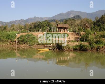 Riverside trama di un agricoltore di sussistenza in Laos riflesso su acque ferme. Foto Stock