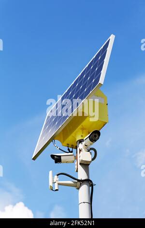 Due telecamere di sicurezza e pannello solare sul palo contro cielo blu su sfondo Foto Stock