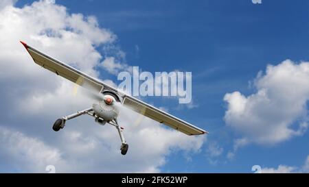 Aereo leggero azionato da un propulsore vola su uno sfondo di cielo blu nuvoloso. CopySpace. Foto Stock