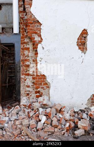 Angolo di un edificio distrutto con un muro danneggiato e. un mucchio di mattone rotto Foto Stock