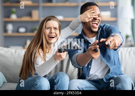 Coppia multiculturale allegra divertirsi a casa, giocando i videogiochi insieme Foto Stock