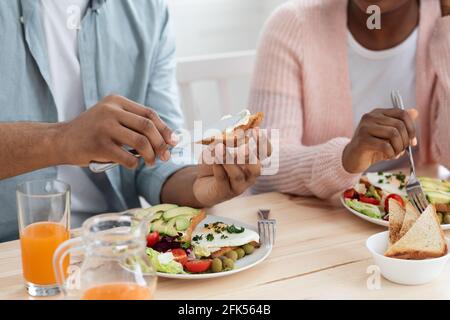 Pasto gustoso. Primo piano di Unriconoscable Black Man e Donna mangiare prima colazione Foto Stock