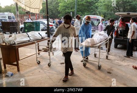 Nuova Delhi, India. 28 Apr 2021. (NOTA PER I REDATTORI: Immagine della morte) l'operaio sanitario e i membri della famiglia portano un corpo del loro parente che è morto dal virus Coronavirus Covid-19 per la cremazione a un crematorio. L'India si trova ad affrontare il numero di casi di Covid-19 in più rapida crescita al mondo, con 360,927 nuove infezioni confermate, il numero più alto di giorni nel paese e più di 3,293 decessi nel mese di aprile 2021. Credit: SOPA Images Limited/Alamy Live News Foto Stock