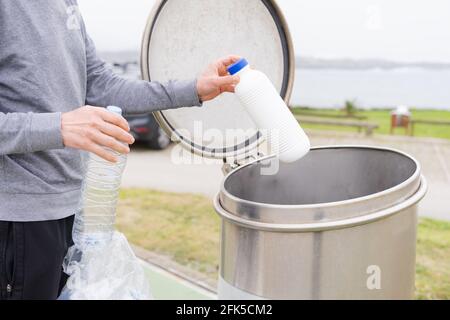 Uomo che getta contenitori di plastica al punto di riciclaggio. Responsabilità sociale. Concetto di riciclaggio. Foto Stock