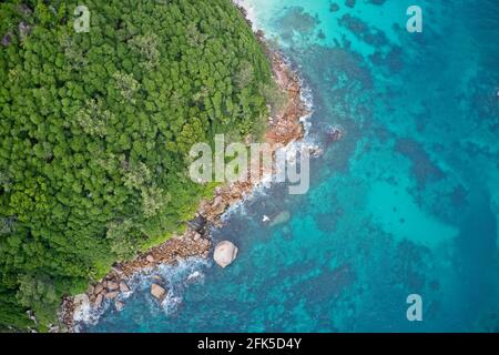 Drone campo di vista delle acque turchesi blu che incontrano la costa Praslin, Seychelles. Foto Stock