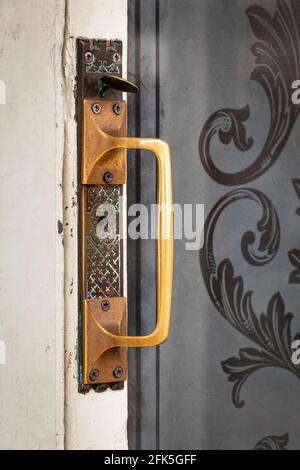 Maniglia per porta in ottone con chiusura a scatto su porta in legno con inciso pannello di vetro Foto Stock