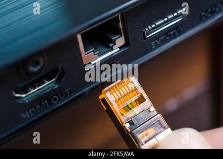 Mano maschio che collega un cavo RJ45 alla porta di rete Di un notebook nero Foto Stock