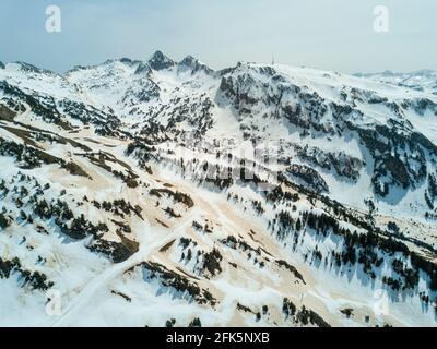 Vista aerea presa da un drone, che mostra le macchie di neve di colore marrone arancio, risultanti dalla polvere del Sahara sulle pendici rocciose di alcune delle parti più alte dei Pirenei nella stazione sciistica di Baqueira nel nord della Catalogna, Spagna. © Time-Snap Foto Stock