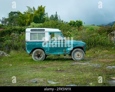 Guatapé, Antioquia, Colombia - 3 aprile 2021: Green Blue Jeep parcheggiata su strada sterrata, erba e erbacce Foto Stock
