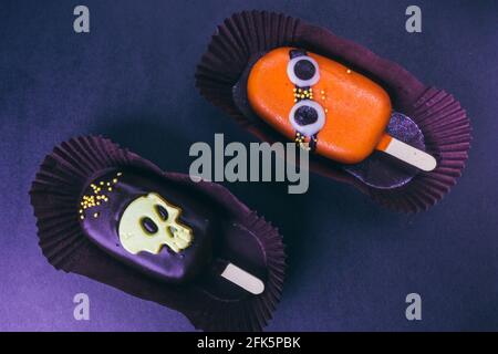 Halloween ghiacciato tratta cupcakes in cioccolato con facce mostro. Foto Stock