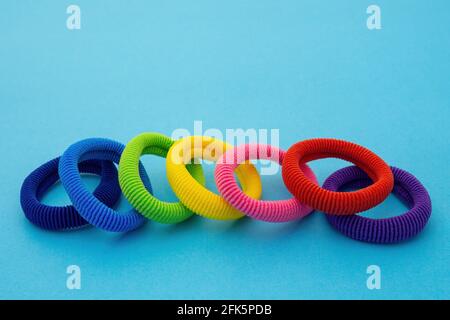 Scrunchies, cravatte elasticizzate colorate, supporti per coda di rondine per bambini in cotone, fasce per capelli senza cuciture su sfondo blu. Foto Stock