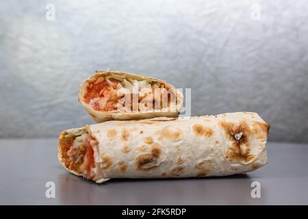 shaurma in pita con ripieno di pollo e verdure su fondo grigio. Foto Stock