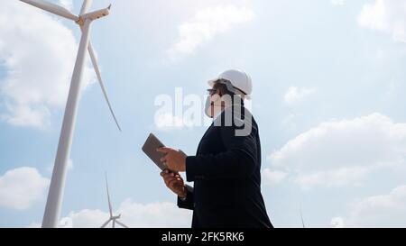 Ingegnere windmills manager indossare maschera viso e compressa di supporto con turbina eolica in background Foto Stock