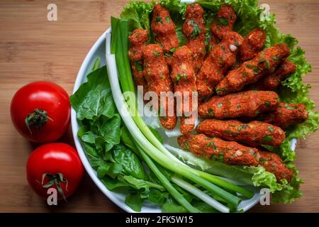 Polpette crude turche (CIG kofte; piatto di carne cruda) con insalata, cipolla e pomodoro. Primo piano Foto Stock