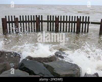 I palchi di ferro e i grandi massi fanno parte delle difese marine dove il fiume Blyth incontra il Mare del Nord; Southwold, Suffolk. Foto Stock